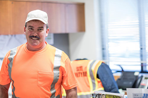 A male ORISE facilities employee wearing high visibility clothing