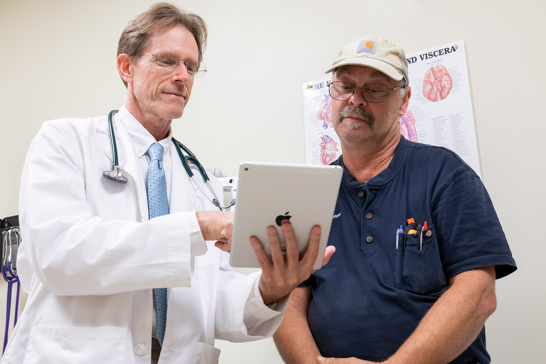 A male physician and a male patient look at health information on a tablet