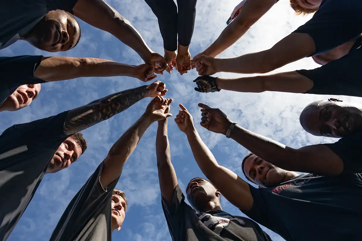 Image of a group of people in a circle with arms extended