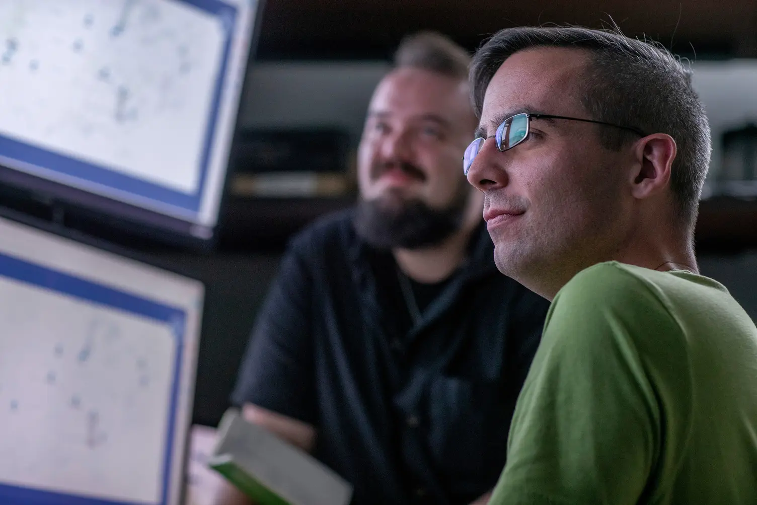 Business men in a dark room standing in front of a large data display