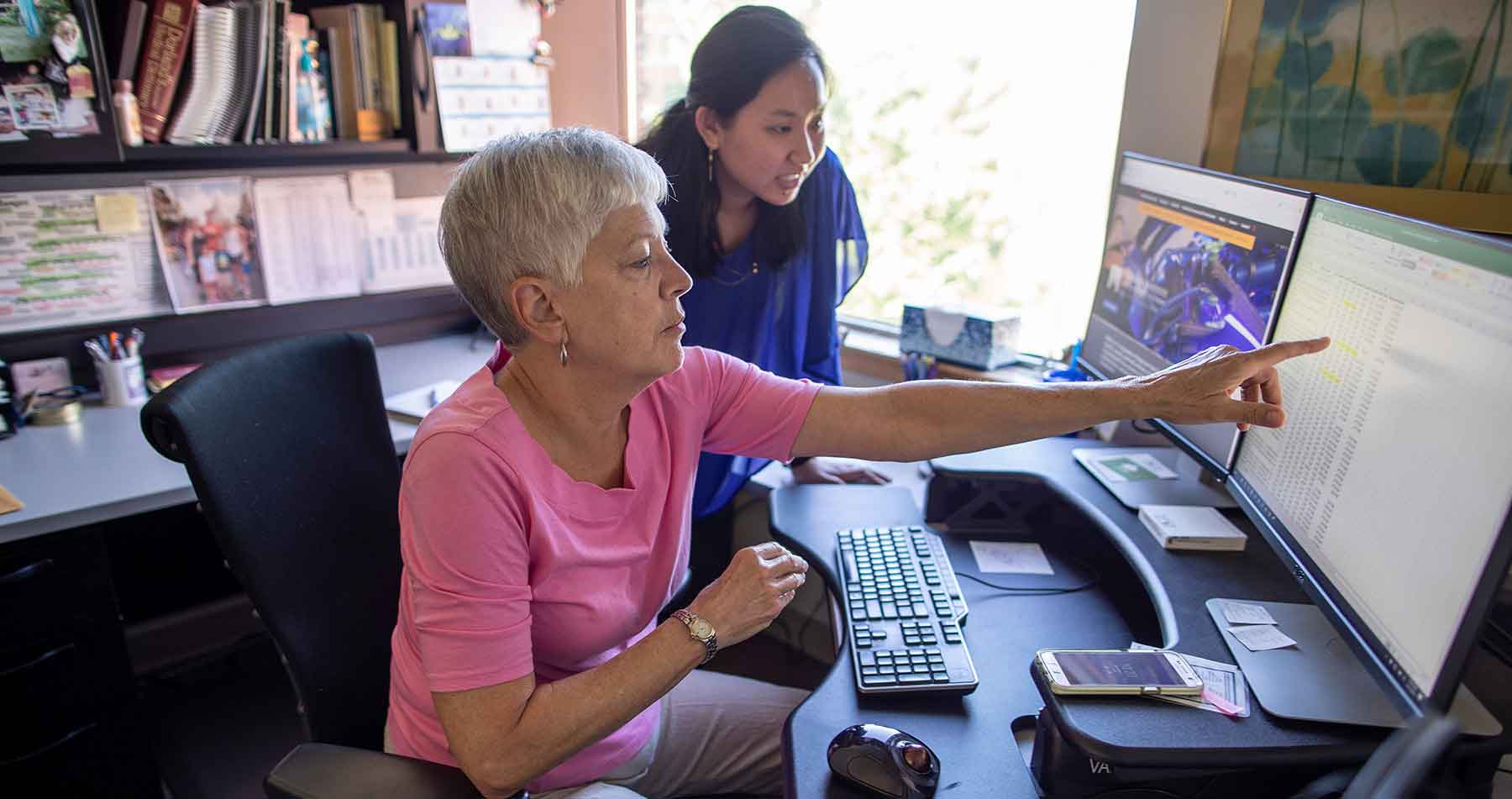 Two female researchers examine worker health information on a computer