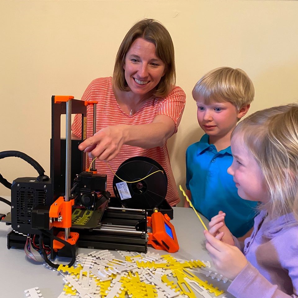 Mom shows her children how a 3D printer creates earguards
