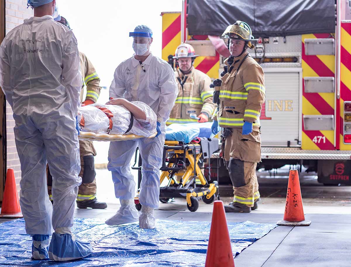 Fire and medical professionals transport a patient during a REAC/TS continuing medical education course