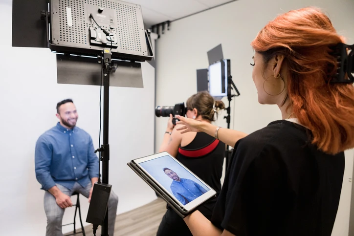 Photographer shoots man's photos while assistant gives directions