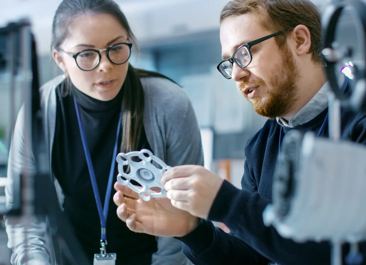 A pair of engineers in a modern laboratory discussing prototype built with the help of 3D printer