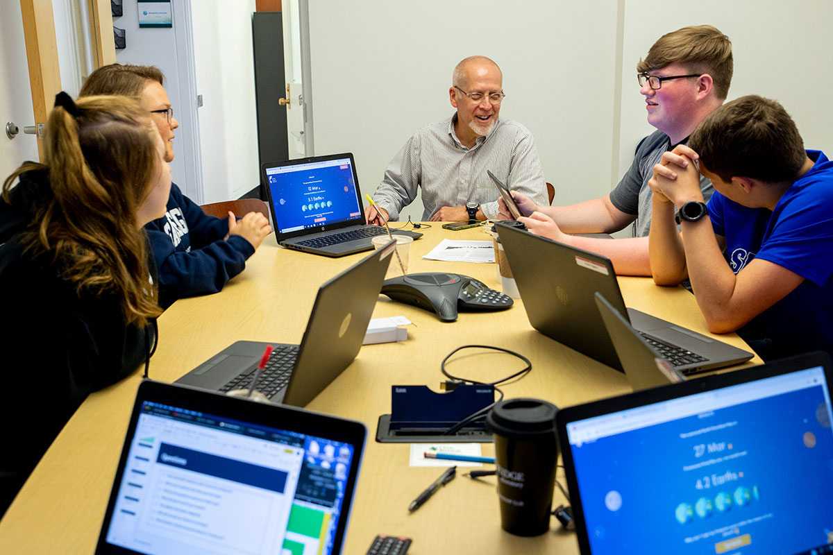A male mentor works with high school students during the ARC/ORNL Summer Research Institute