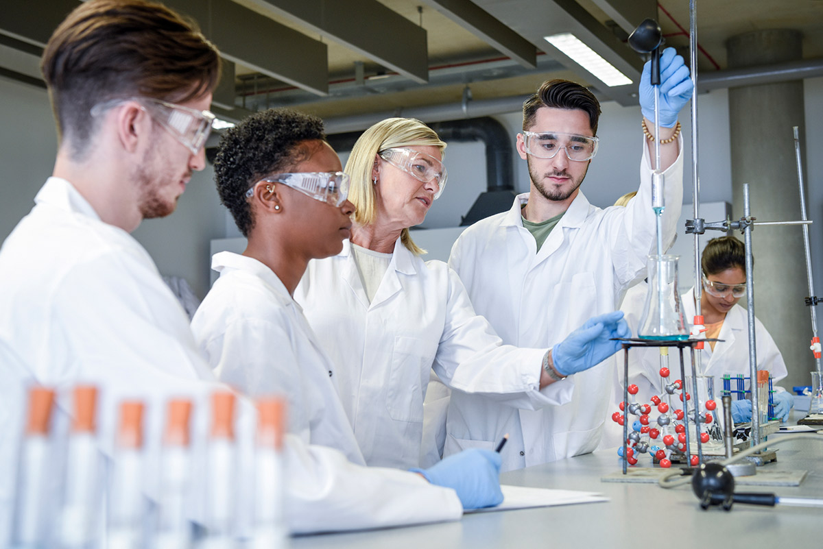 A mentor instructs a group of interns in a laboratory setting