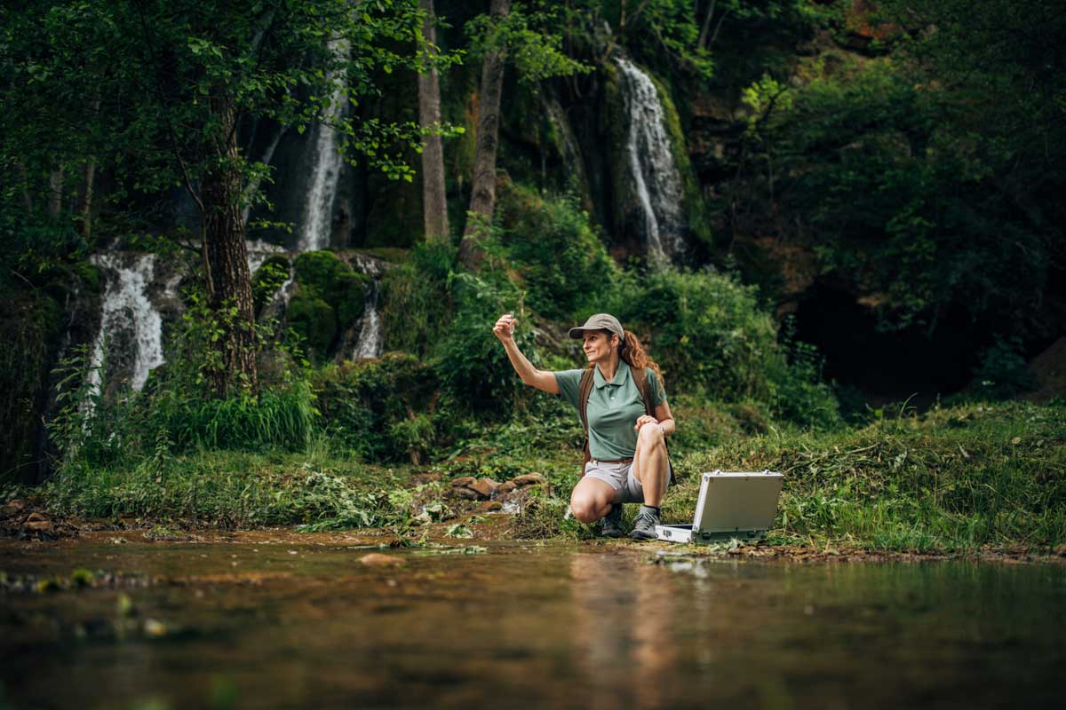 A postdoctoral researcher collects a water sample 
